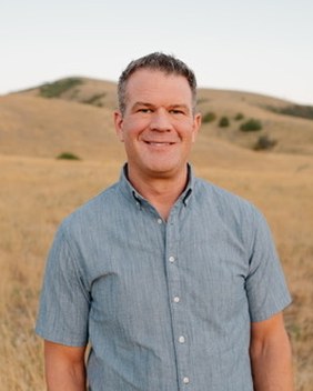 Christian Sorensen standing in a field of tall golden grass, smiling